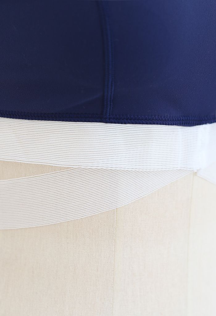 Conjunto de sutiã esportivo com faixa contrastante e legging assimétrica